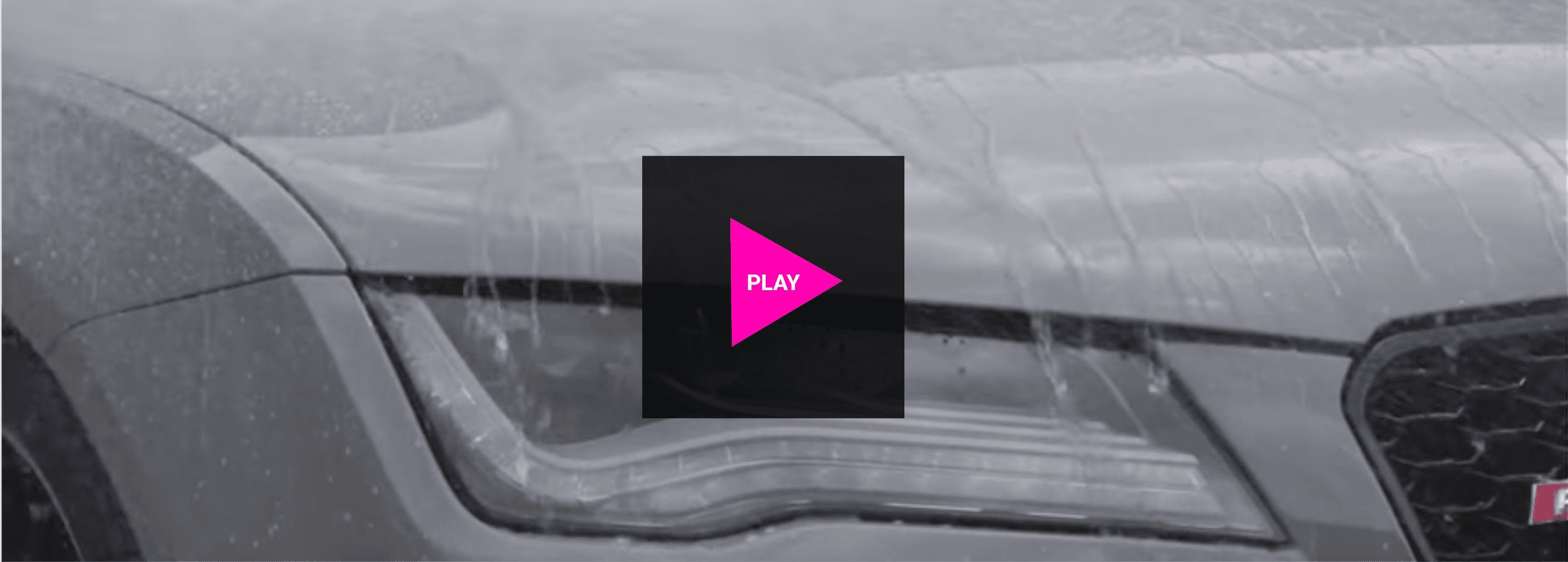 A black and white photo of a car in the rain with a pink play button.